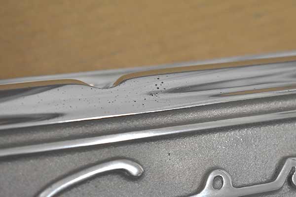 The second valve cover has a very thin fin above the script and a large set of porosity.